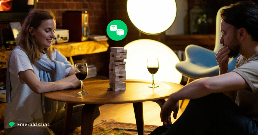 A man and a woman sitting at a table with wine glasses while playing Jenga